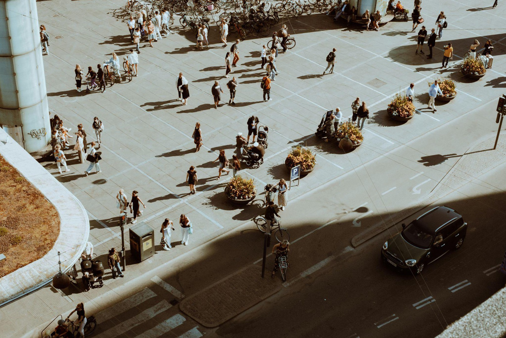 Praça urbana com pessoas, bicicletas e vegetação